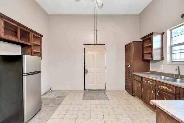 kitchen with ceiling fan, a textured ceiling, stainless steel fridge, and sink