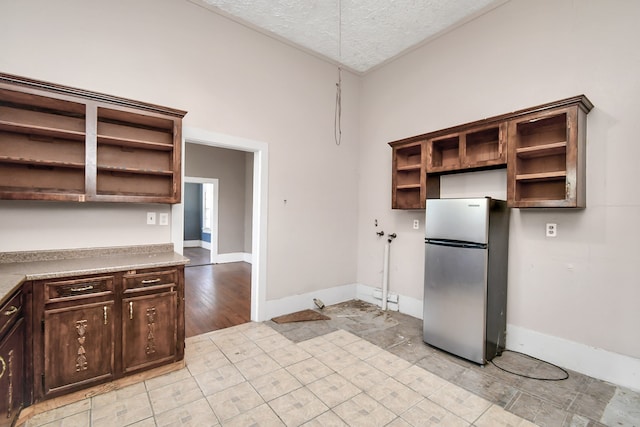 kitchen featuring light wood-type flooring, a textured ceiling, dark brown cabinetry, and stainless steel fridge