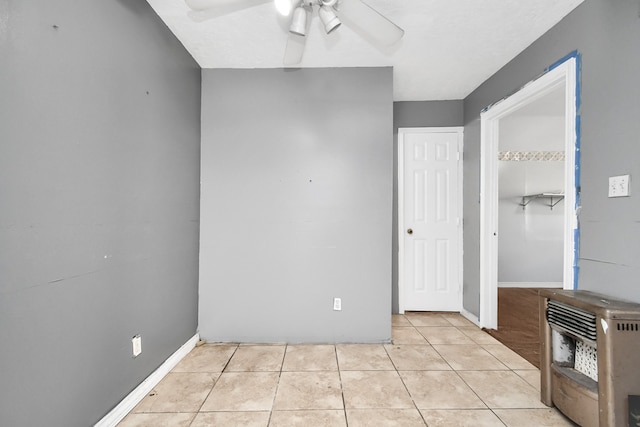 interior space with ceiling fan, heating unit, and light tile patterned floors