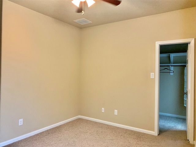 unfurnished bedroom featuring carpet, ceiling fan, a walk in closet, and a closet