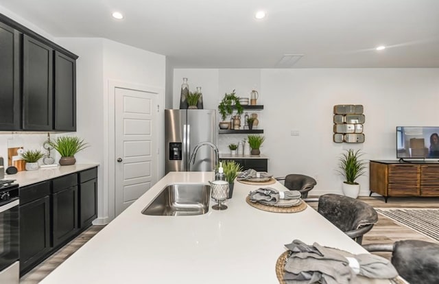 kitchen with a breakfast bar area, light hardwood / wood-style flooring, stainless steel appliances, and sink