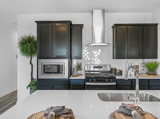 kitchen featuring appliances with stainless steel finishes, wall chimney exhaust hood, dark brown cabinets, hardwood / wood-style flooring, and sink