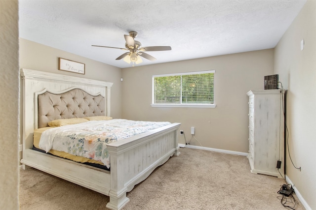 bedroom featuring a textured ceiling, light carpet, and ceiling fan