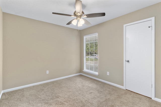 carpeted spare room featuring ceiling fan