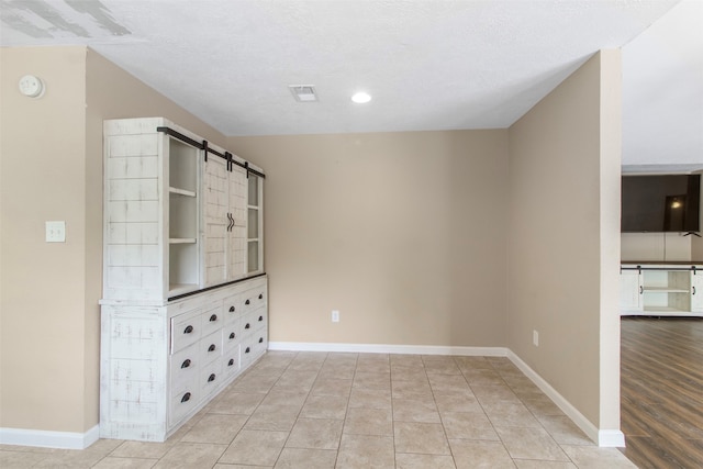 interior space featuring a textured ceiling, built in features, a barn door, and light tile patterned flooring