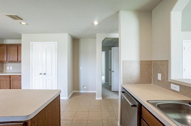 kitchen with sink, backsplash, light tile patterned floors, and stainless steel dishwasher