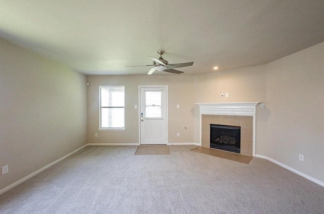 unfurnished living room with ceiling fan, light colored carpet, and a fireplace