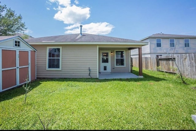 back of house featuring a patio, a yard, and a storage unit