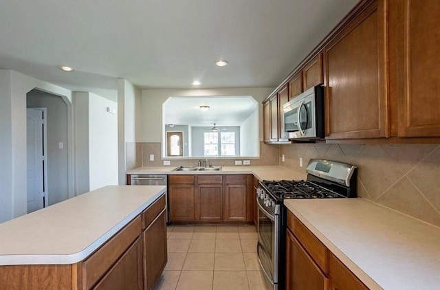 kitchen featuring decorative backsplash, a kitchen island, light tile patterned floors, stainless steel appliances, and sink