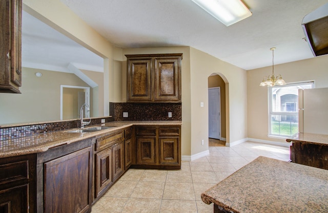 kitchen with white refrigerator, backsplash, ornamental molding, sink, and a notable chandelier