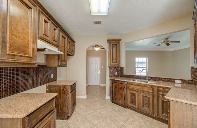 kitchen featuring ceiling fan, kitchen peninsula, sink, tasteful backsplash, and crown molding