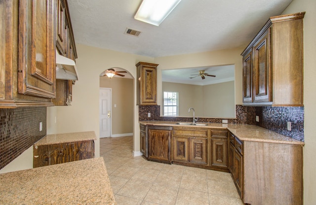 kitchen with light tile patterned flooring, tasteful backsplash, a textured ceiling, ceiling fan, and sink