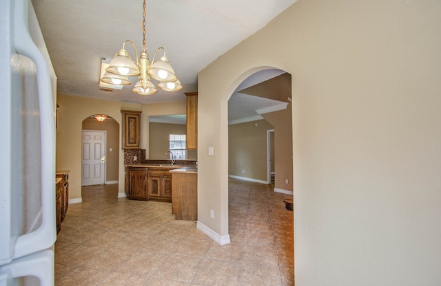 corridor with an inviting chandelier, light tile patterned floors, and sink