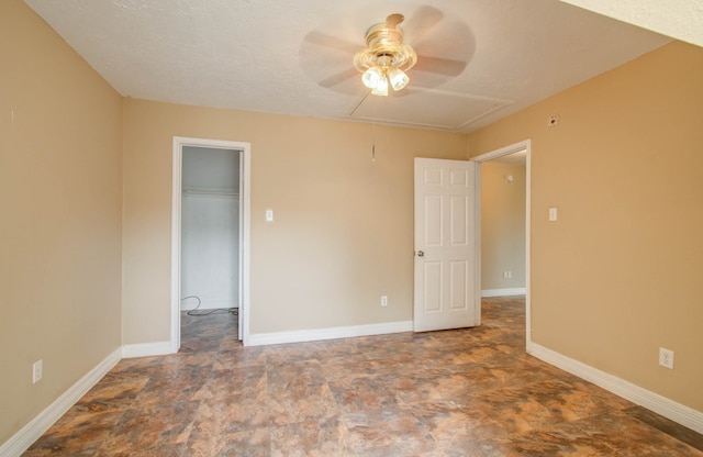 unfurnished bedroom featuring a textured ceiling, a spacious closet, ceiling fan, and a closet