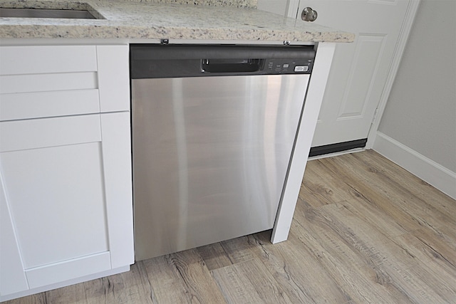 interior details featuring light stone counters, white cabinets, sink, dishwasher, and light hardwood / wood-style floors