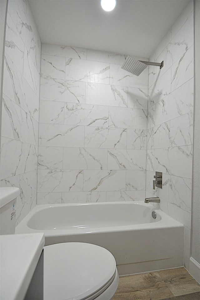 full bathroom featuring wood-type flooring, tiled shower / bath combo, vanity, and toilet