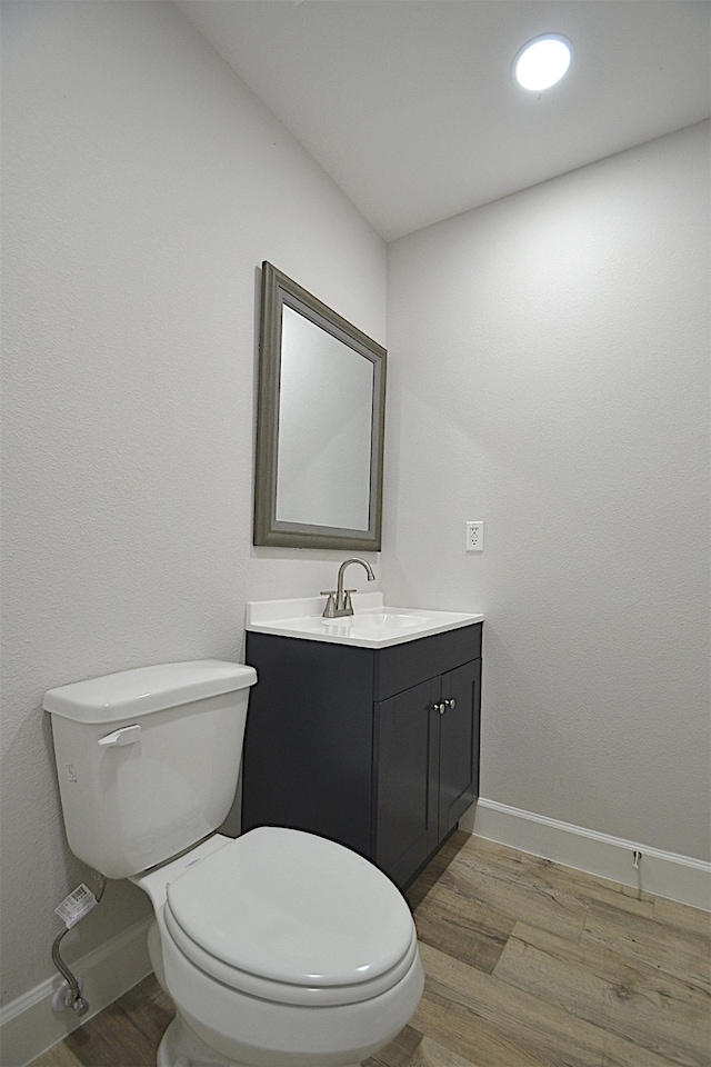 bathroom featuring wood-type flooring, vanity, and toilet