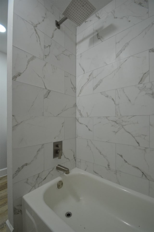 bathroom with tiled shower / bath combo and hardwood / wood-style floors