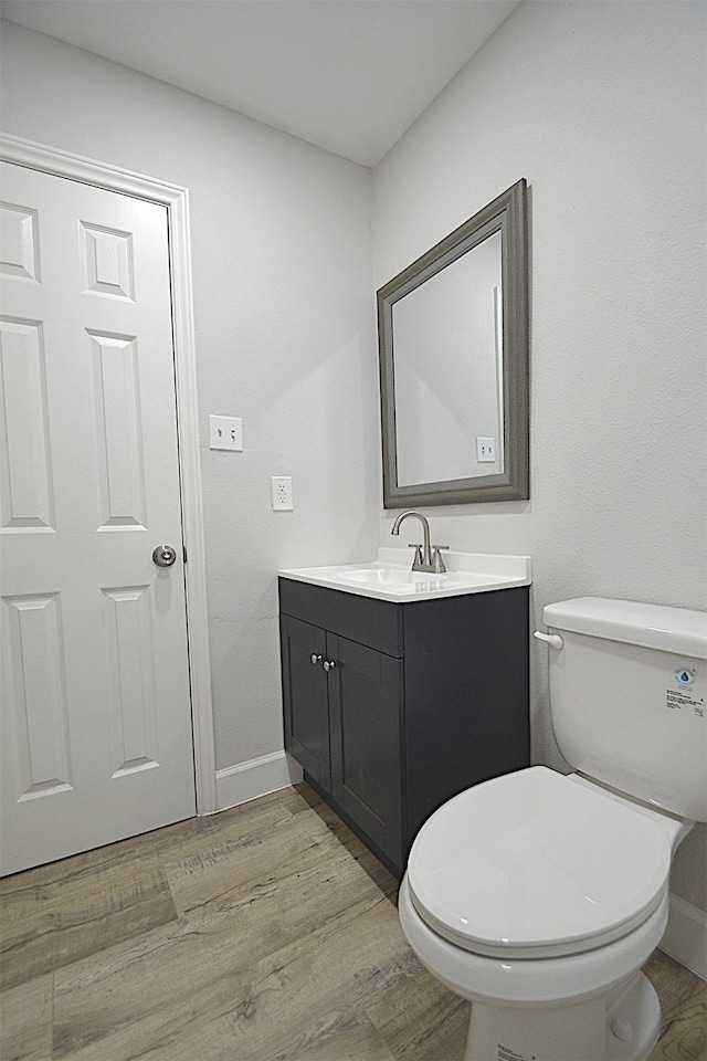 bathroom with vanity, toilet, and hardwood / wood-style flooring