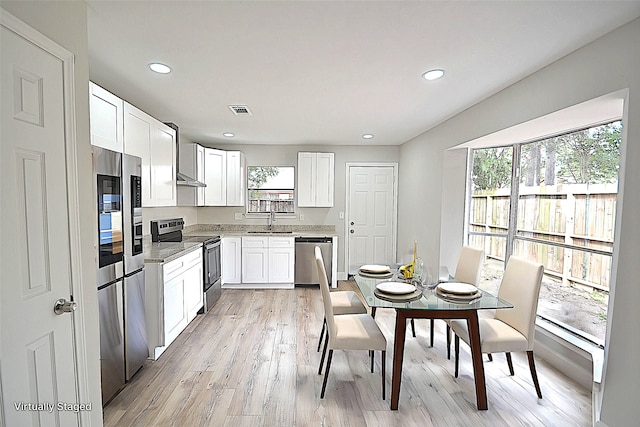 kitchen with appliances with stainless steel finishes, light hardwood / wood-style floors, white cabinets, light stone countertops, and sink