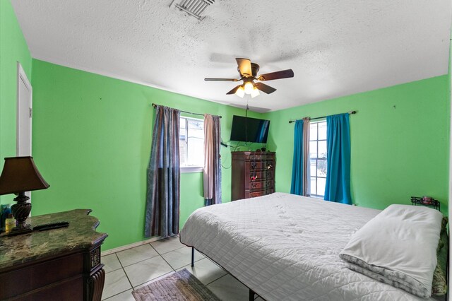 tiled bedroom featuring multiple windows, a textured ceiling, and ceiling fan