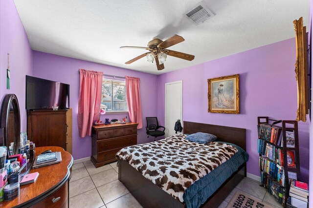 tiled bedroom with a textured ceiling and ceiling fan