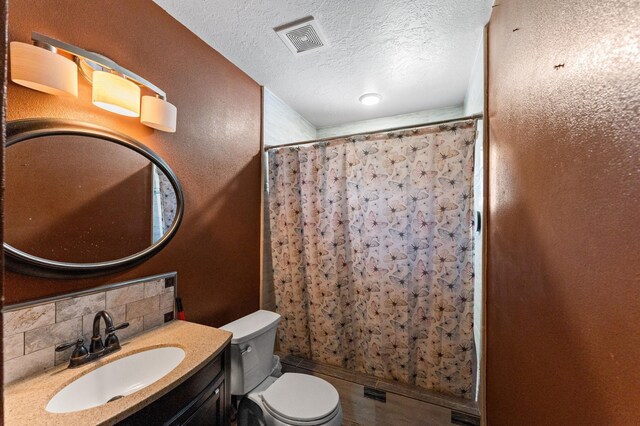 bathroom with a textured ceiling, tasteful backsplash, a shower with curtain, vanity, and toilet