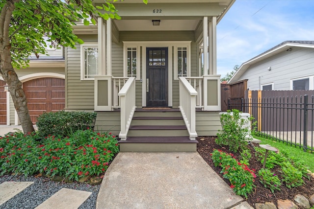 view of exterior entry featuring a garage and covered porch