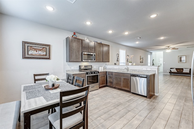 kitchen featuring light hardwood / wood-style floors, sink, kitchen peninsula, appliances with stainless steel finishes, and ceiling fan