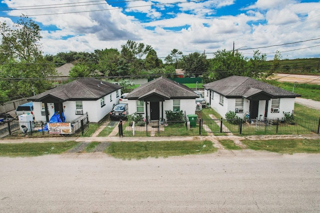 bungalow-style home with a fenced front yard and dirt driveway