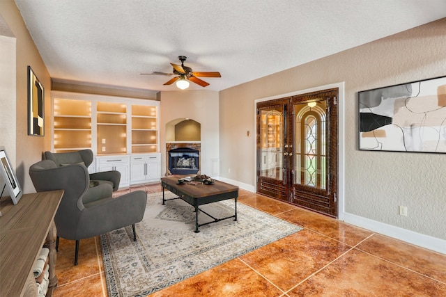 living room featuring tile patterned floors, a textured ceiling, built in features, and ceiling fan