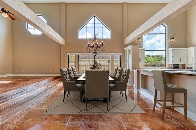 dining room with a towering ceiling, hardwood / wood-style floors, and ceiling fan with notable chandelier