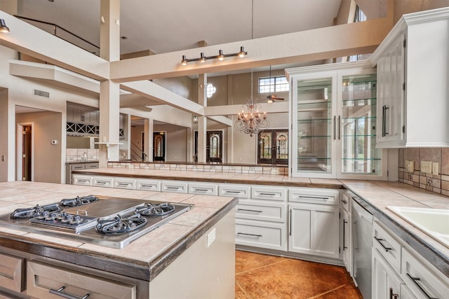 kitchen featuring decorative backsplash, white cabinetry, stainless steel appliances, and a towering ceiling