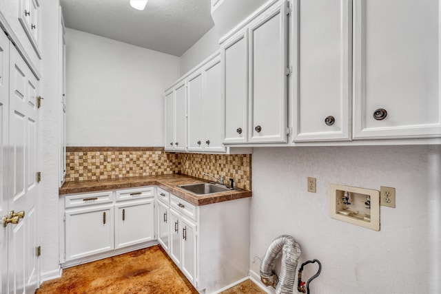 clothes washing area with hookup for a washing machine, a textured ceiling, cabinets, and sink