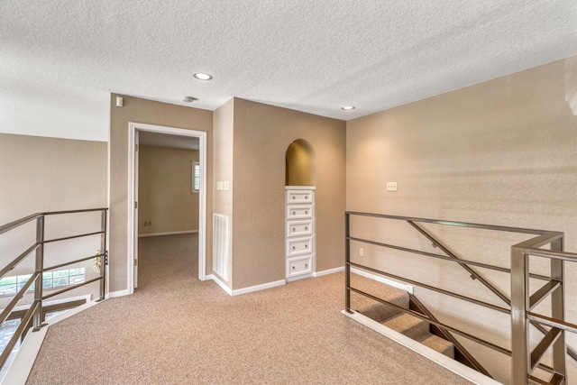 hall featuring a textured ceiling and carpet floors