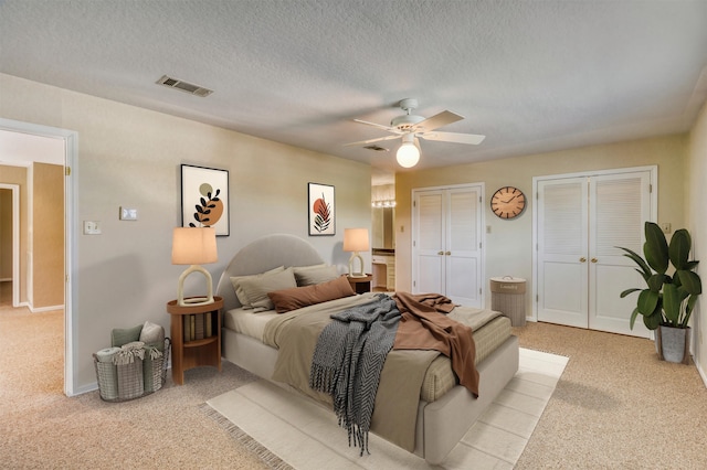 bedroom with a textured ceiling, light colored carpet, connected bathroom, and ceiling fan