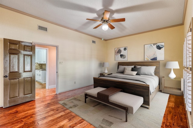 bedroom featuring ornamental molding, a textured ceiling, hardwood / wood-style flooring, and ceiling fan