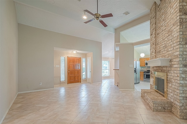 unfurnished living room featuring ceiling fan, light tile patterned flooring, a brick fireplace, a textured ceiling, and high vaulted ceiling