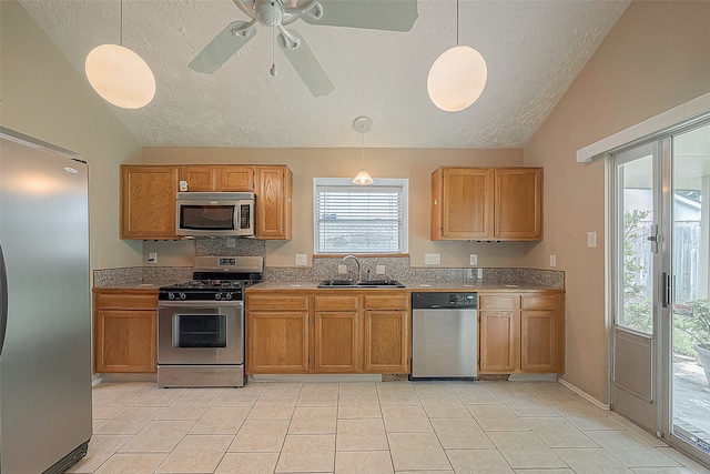 kitchen with ceiling fan, lofted ceiling, hanging light fixtures, sink, and stainless steel appliances