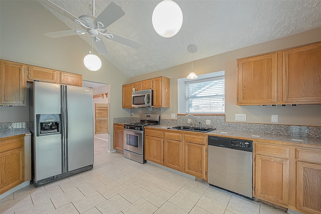 kitchen with ceiling fan, pendant lighting, sink, stainless steel appliances, and vaulted ceiling