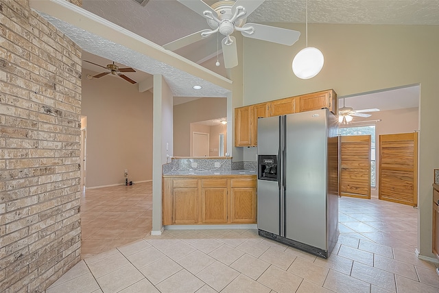 kitchen featuring ceiling fan, a textured ceiling, stainless steel fridge with ice dispenser, and high vaulted ceiling