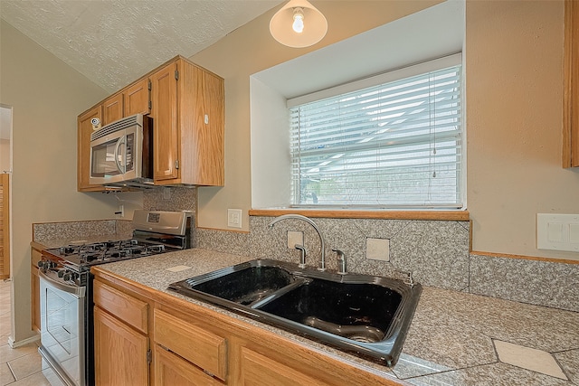 kitchen featuring appliances with stainless steel finishes, decorative backsplash, a textured ceiling, lofted ceiling, and sink