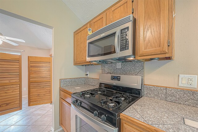 kitchen featuring ceiling fan, appliances with stainless steel finishes, light tile patterned floors, and a textured ceiling