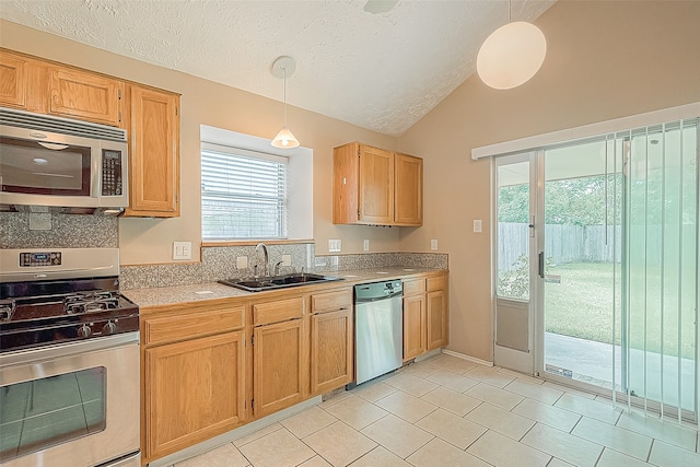 kitchen with a textured ceiling, sink, lofted ceiling, hanging light fixtures, and stainless steel appliances