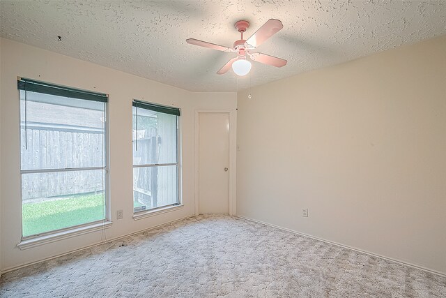 carpeted spare room featuring ceiling fan and a textured ceiling