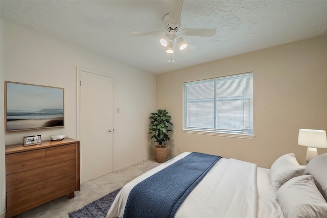 bedroom featuring light carpet, ceiling fan, and a textured ceiling