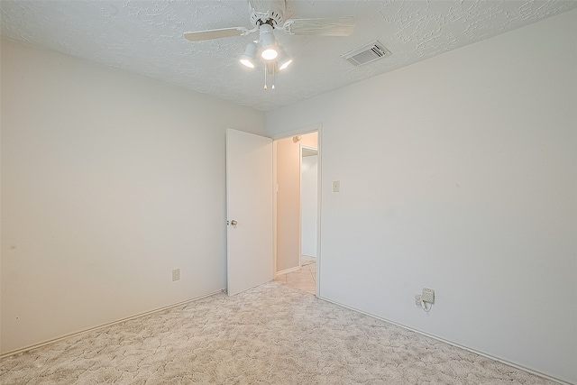 empty room featuring a textured ceiling, light carpet, and ceiling fan