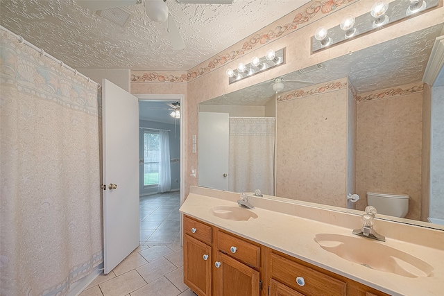 bathroom with ceiling fan, vanity, a textured ceiling, tile patterned floors, and toilet