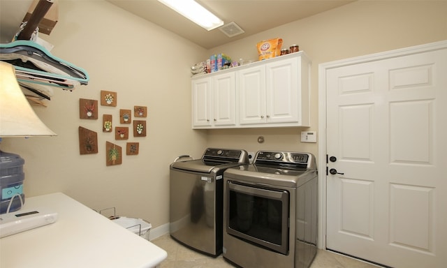 clothes washing area with light tile patterned flooring, washing machine and clothes dryer, and cabinets