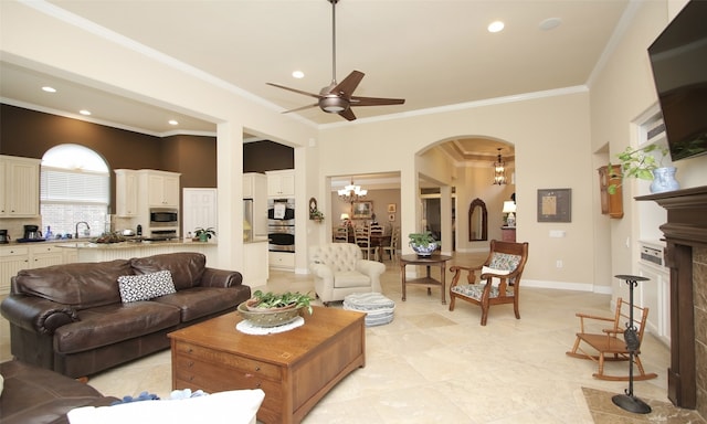 tiled living room featuring sink, ceiling fan with notable chandelier, and ornamental molding